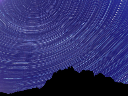 Long exposure image showing Night sky star trails over mountainsの写真素材