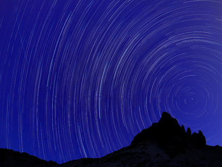 Long exposure image showing Night sky star trails over mountainsの写真素材