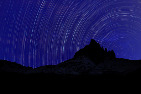 Long exposure image showing Night sky star trails over mountainsの写真素材