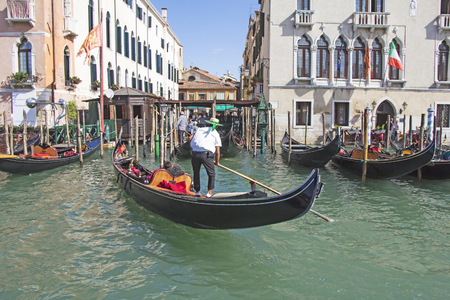 Venetian gondolier in the gondola is transported tourists through canal waters of Venice Italyの写真素材