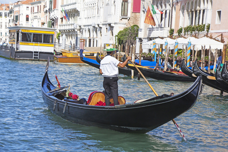 Venetian gondolier in the gondola is transported tourists through canal waters of Venice Italyの写真素材