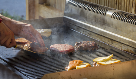 Chef preparing burgers at the barbecue outdoorsの写真素材