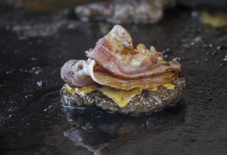 Preparing burgers with bacon at the barbecue outdoorsの写真素材