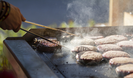Chef preparing burgers at the barbecue outdoorsの写真素材