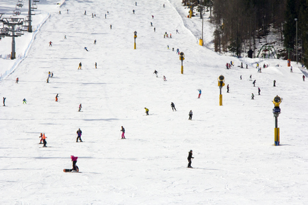 Lots of skiers and snowboarders on the slope at ski resortの写真素材