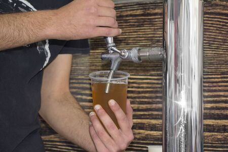 Barmen filling plastic glass with light beerの写真素材
