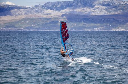 Young windsurfer in the waves in the seaの写真素材