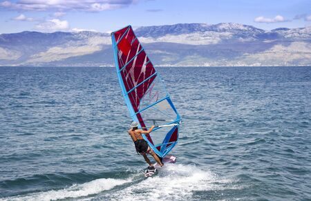 Young windsurfer in the waves in the seaの写真素材
