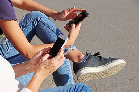 Two young girls watching smart mobile phonesの写真素材