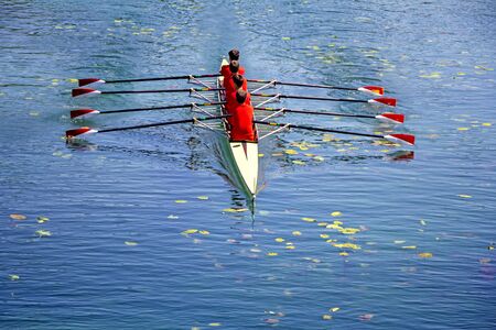 Men's quadruple rowing team on blue water, top view