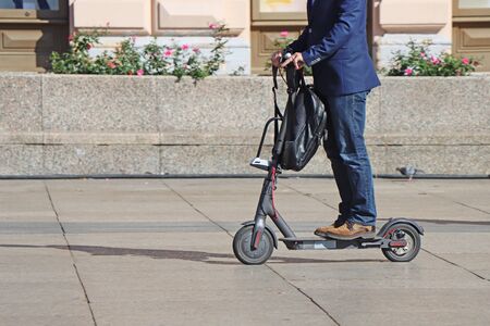 Man riding a kick scooter at the city squareの写真素材
