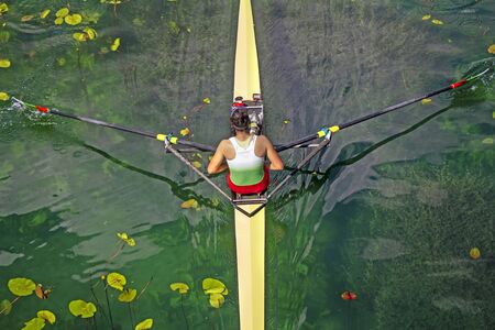 Woman Single sculls rower during the start of a rowing on the tranquil lakeの写真素材