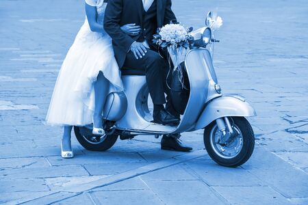 Young newlywed just married, posing on an old scooter. Classic Blue  2020 year color.の写真素材