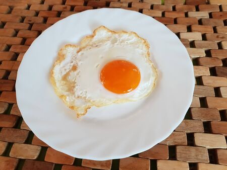 Fried egg on a white plate on a wooden backgroundの写真素材
