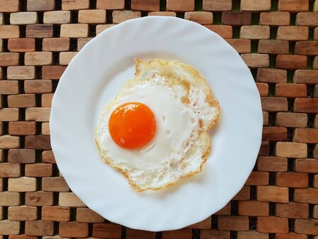 Fried egg on a white plate on a wooden backgroundの写真素材
