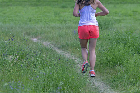 Young woman running in nature on a rural roadの写真素材