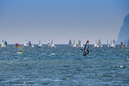 Windsurfer surfing and sailboats sailing the wind on waves In Lago di Garda Lakeの写真素材