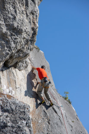 Young man climbing natural high rocky wallの写真素材