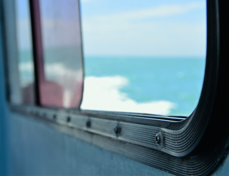 A boats window is opening to caribbean blue depicting the freedom of vacation and beauty of world