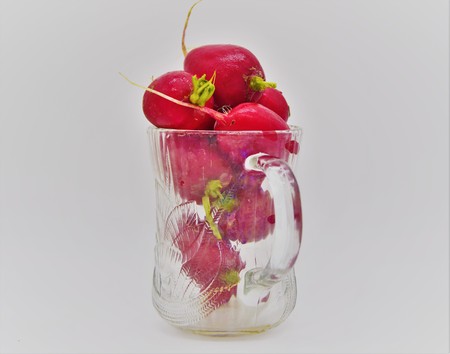 Eight healthy Red Radishes in a translucent coffee mug depicting a healthy drinkの写真素材