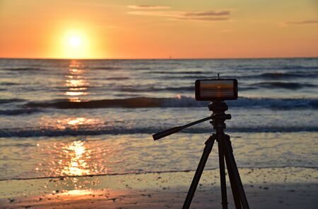 Tripod, smart cell Phone, beach and sunsetの写真素材