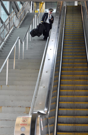 Newark, NJ, USA - September 19, 2023 - A commercial pilot jas to lift and drag down suitcases inside the train station because te escalator is not workingのeditorial素材