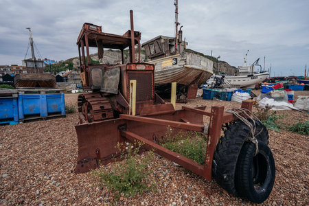 Hastings Port, East Sussex / UK -  2020.08.08: Bulldozers at Hastings fishing boats on the beach at...