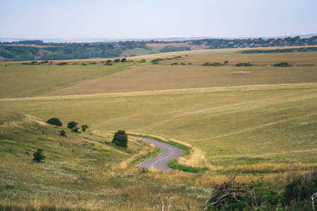 A summer country road runs across fields of chalk grassland at Beachy Head on the Sussex coast of the South Downs hillsの写真素材