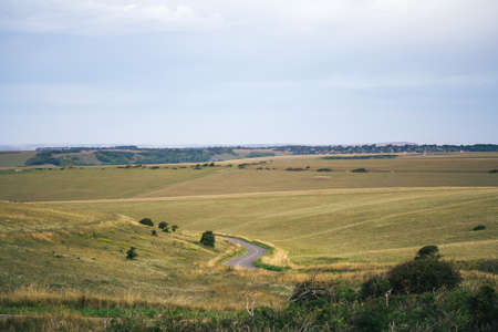 A summer country road runs across fields of chalk grassland at Beachy Head on the Sussex coast of the South Downs hillsのeditorial素材
