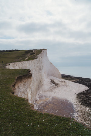 Seaford, East Sussex | UK. Chalk rock cliffs on the Sussex coast with pebble beach and sea on cloudy...