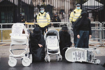 Westminster, London | UK -  2021.05.08: Extinction Rebellion activists kneeling in front of Downing Street with White Baby Pramsのeditorial素材