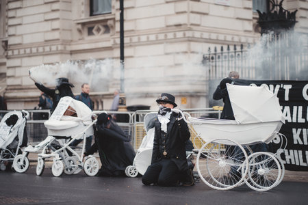 Westminster, London | UK -  2021.05.08: Extinction Rebellion activists kneeling in front of Downing Street with White Baby Prams with smoke granades in the backgroundのeditorial素材
