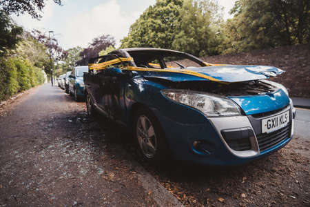 London | UK - 2021.06.12: An abandoned, stolen burnt out blue car parked on the sideway parking spotÐ± tied with yellow do not cross stripeのeditorial素材