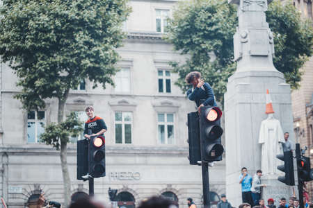 London | UK - 2021.07.12: Young English football fan sitting on the top of traffic light at Trafalgar Square without shirtのeditorial素材