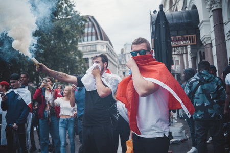 London | UK - 2021.07.12: English fans with flags covering their faces in smoke at Leicester Square to watch the Final Euro 2020 Football gameのeditorial素材