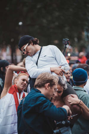 London | UK - 2021.07.12: Football fan sitting on his girlfriends shoulders in Leicester squareのeditorial素材