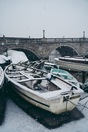 Richmond Upon Thames, London | UK -  2021.01.24: Boats covered in snow and moored on the river in...