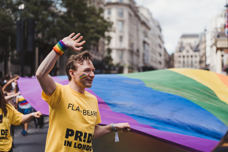 London / UK - 02/07/2022: People with huge rainbow flag celebrating London LGBTQ Pride Paradeのeditorial素材