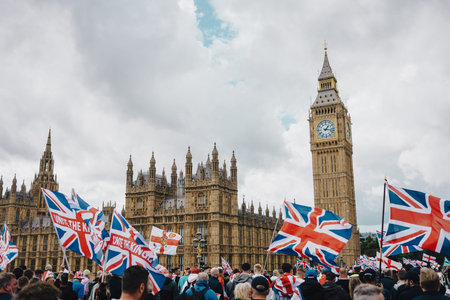 London, UK â€“ 2025.09.13 â€“ Protesters wave Union Jack and England flags outside Houses of Parliament and Big Ben during Free Speech rally in Westminster.
