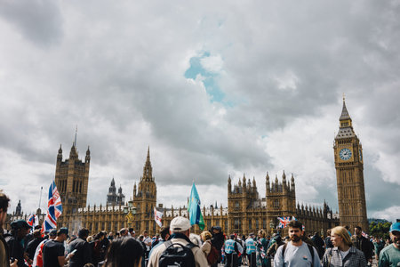 London, UK â€“ 2025.09.13 â€“ Protesters carrying Union Jack and other flags gather outside Houses of Parliament and Big Ben during Free Speech rally.