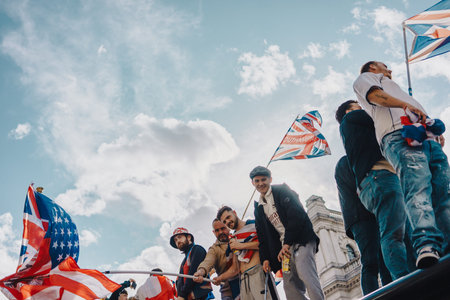London, UK â€“ 2025.09.13 â€“ A group of protesters wave Union Jack and England flags while standing on a rooftop during a Free Speech protest in Westminster. A moment of activism and solidarity.