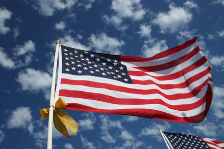 American Flag with a Yellow Ribbon Blowing in the Windの写真素材