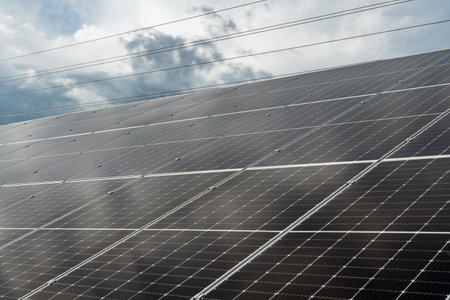 A field of solar panels efficiently captures sunlight to generate renewable energy, set against a backdrop of dark, stormy clouds.の写真素材