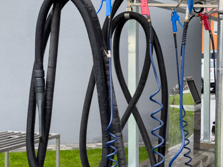 A variety of high-pressure car washer guns hang at a car wash. These essential tools are organized and ready for work, demonstrating efficient cleaning for vehicles.の写真素材