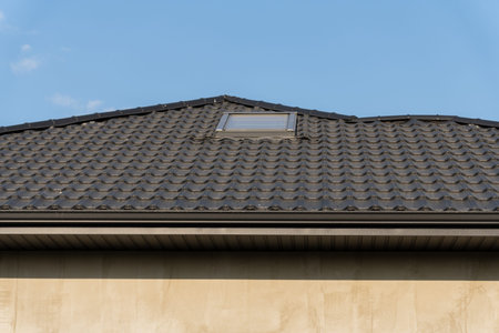 The stylish roof of a contemporary house showcases a sleek tiled design with a skylight, harmonizing...