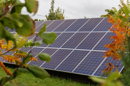 Solar panels stand prominently in a vibrant garden, surrounded by greenery and autumn foliage,...