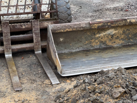 A compact loader equipped with a bucket attachment rests on a construction site, surrounded by dirt...