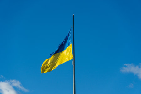 A vibrant Ukrainian flag displays bright blue and yellow colors against a backdrop of clear blue skies. This flag represents the spirit of freedom and patriotism in Ukraine.の写真素材