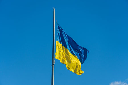 The vibrant blue and yellow colors of the Ukrainian flag flutter against a pristine blue sky.の写真素材