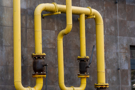 Yellow gas pipes are installed on a building's exterior, connecting energy sources effectively. The...